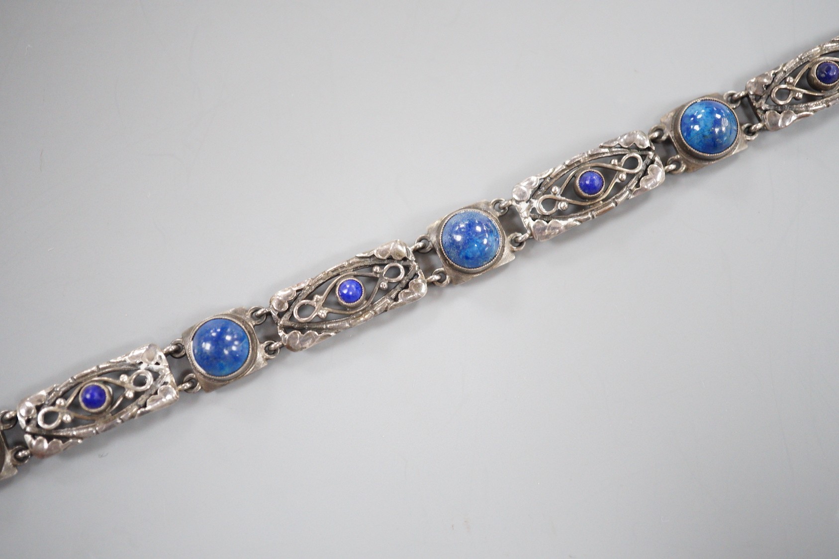 A stylish early 20th century white metal and two colour ten stone lapis lazuli?? or possibly enamel?? cabochon set bracelet, stamped 'Liberty Sterling', 18.3cm.